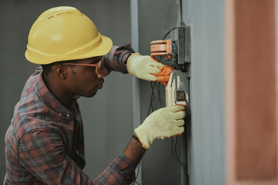 Electrician in a hard hat working on a panel